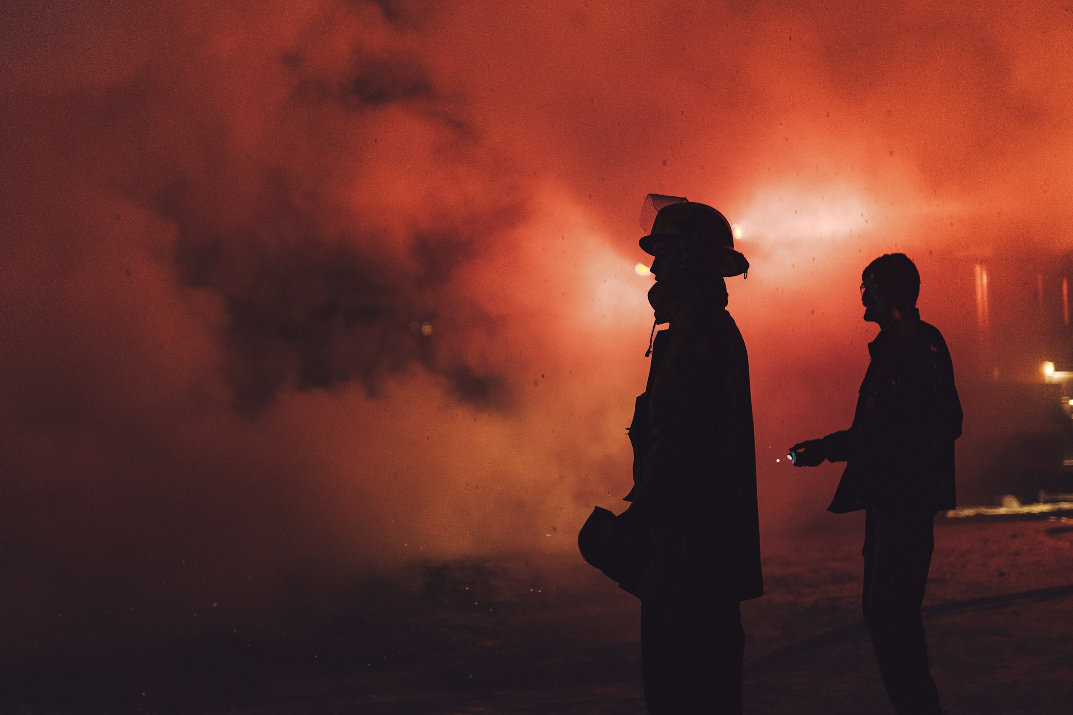 Firefighter silhouette moving through smoke and firelight
